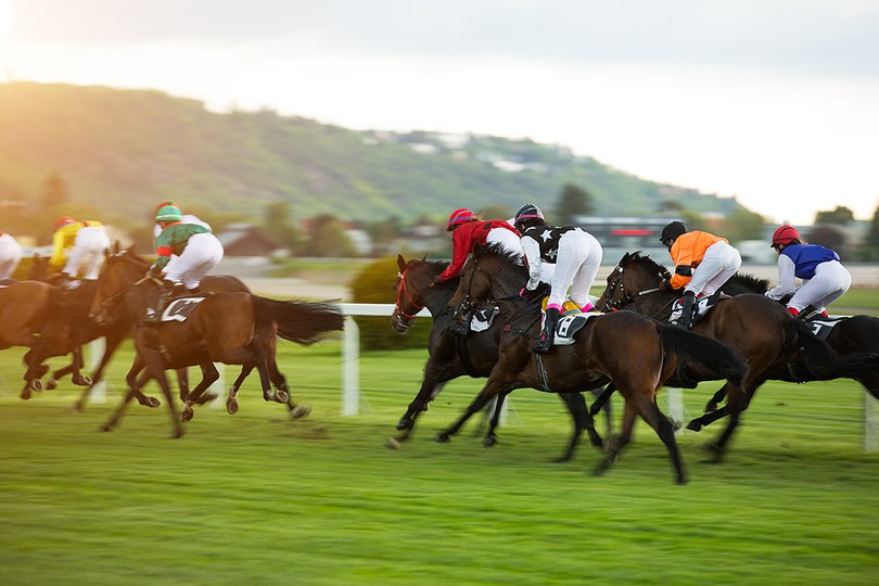 Horses Racing Against Blurred Track